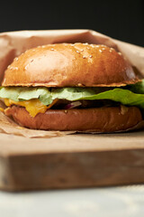 Burger on a turf board. Burger with brioche, beef, slat romaine, tomato, cucumber, cheddar cheese and onion.  