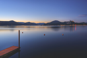 Arona, Italy. Panoramic view from the village of Arona after sunset on Lake Maggiore. On the opposite bank you can see the Rocca Angera, an ancient medieval fortress. June 10, 2022.