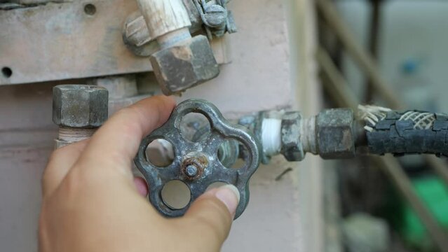 Women's hands opened an old rusty faucet in the street.