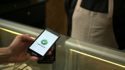Obraz premium Customer paying with contactless NFC payment technology on smartphone device inside business store