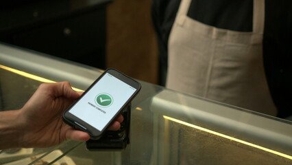 Obraz premium Customer paying with contactless NFC payment technology on smartphone device inside business store