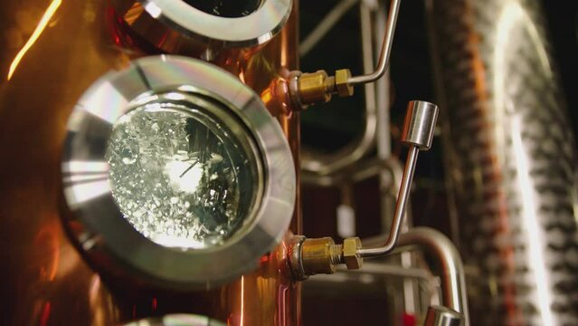 Hot water , liquid boiling inside distillery or filtration tank . Alcohol drink factory or physical experiment laboratory . Cooper or metal machine . Hot temperature , high pressure . Close up