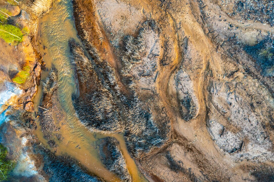 Dried rusty river bed over wasteland grey background, contamination texture, drone view directly above.
