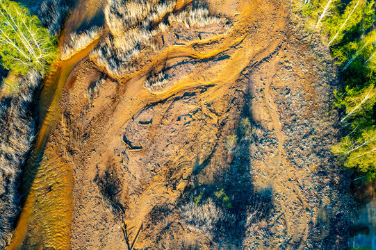 Polluted rusty dirty creek. Nature pollution concept. Water with pieces of ice around the edges. Top view of the yellow stream