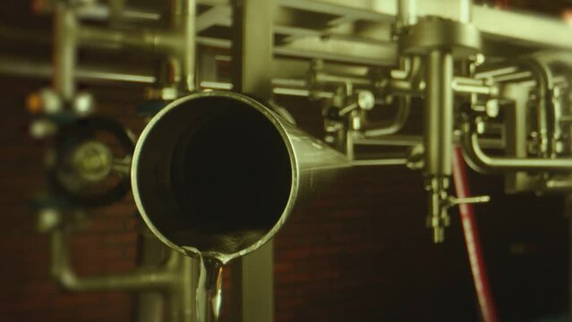 Vodka pouring from big tubes inside professional alcohol production factory . Process of distillation . Camera moving inside pipe . Close up slow motion . Shot on ARRI ALEXA Camera with Laowa lens
