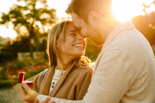 White man smiling and proposing to his girlfriend in park