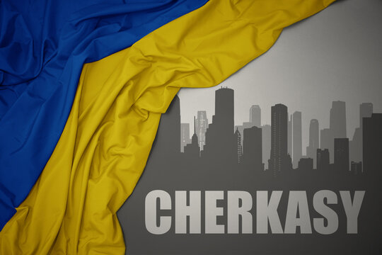 abstract silhouette of the city with text Cherkasy near waving national flag of ukraine on a gray background.