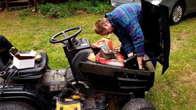 Man fixing his old tractor lawnmower after carburetor breakdown.