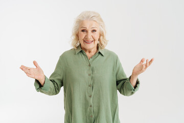 Grey senior woman in shirt smiling while gesturing at camera