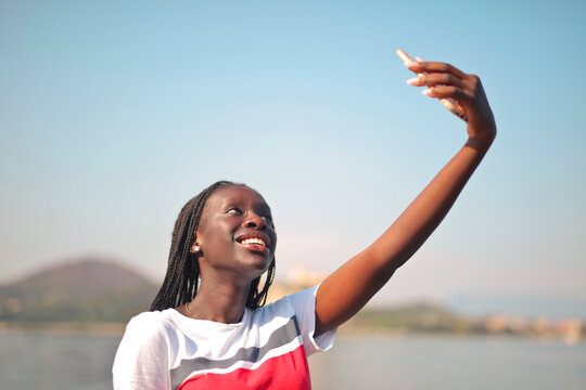portrait of young woman at the lake while taking a selfie