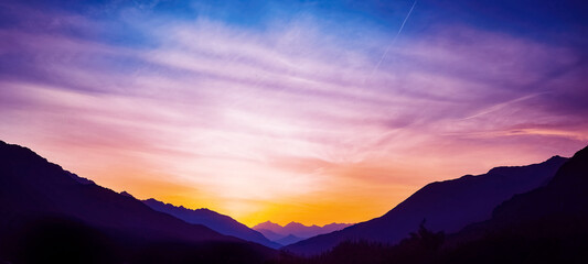 Naklejka na ściany i meble Mountain landscape panorama background - Sunrise or sunset with silhouette of mountains alps and orange sky..