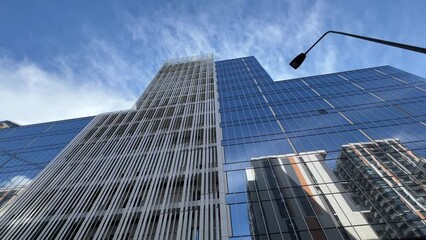 Glassed office building exterior with sky reflection in the windows. Bottom up view. Wide angle shot