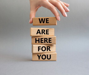 Help symbol. Wooden blocks with words 'We are here for you'. Beautiful grey background. Businessman hand. Business and 'We are here for you' concept. Copy space.
