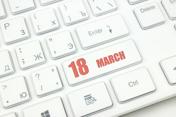 March 18th. Day 18 of month, Calendar date. Cropped view of Modern White Computer Keyboard with calendar date. Concept workspace, freelance, deadline.  Spring month, day of the year concept.