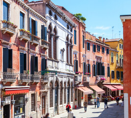 Fototapeta na wymiar Winding street with colorful facades of buildings on a sunny morning, Venice, Italy