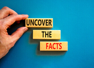 Uncover the facts symbol. Concept words Uncover the facts on wooden blocks on a beautiful blue table blue background. Businessman hand. Business and uncover the facts concept. Copy space.