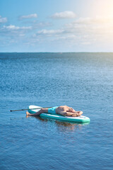 Man lying drifting on paddling board on water