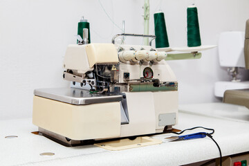 Professional overlock sewing machine with green thread in workshop