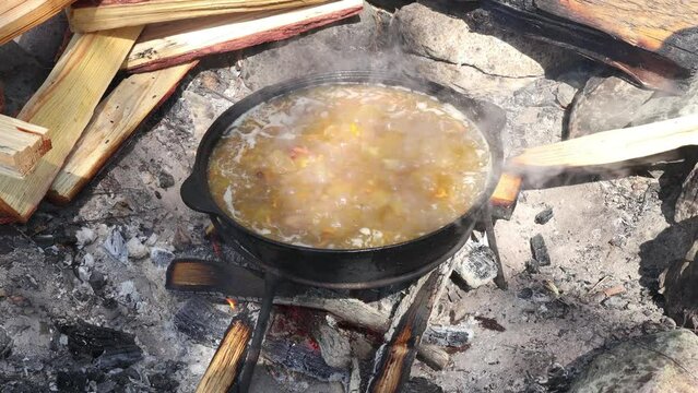 Cooking pilaf or soup outdoors on a campfire. Dishes of the national cuisine of the peoples of the East. Vegetables and meat are cooked in a cauldron.