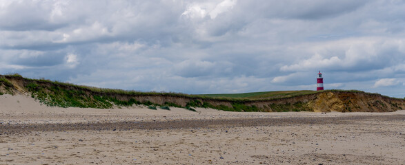 panorama landscape of Happisburgh beach and lighthouse with tall sand dunes and cliffs
