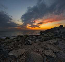 Russia. North-Eastern Caucasus. Dagestan. A picturesque sunrise on the rocky shore of the Caspian Sea, strewn with pebbles, near the central embankment of the city of Makhachkala.