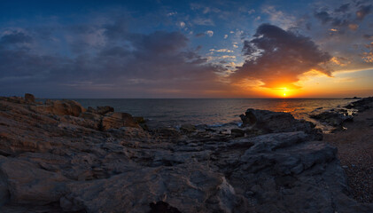 Russia. North-Eastern Caucasus. Dagestan. A picturesque sunrise on the rocky shore of the Caspian Sea, strewn with pebbles, near the central embankment of the city of Makhachkala.