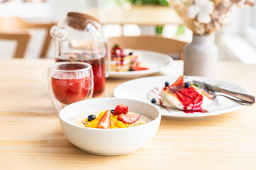 Concept of healthy breakfast in cafe with kinfolk style interior. Breakfast with herbal tea, oatmeal porridge, cottage cheese fritters and pancakes with berry sauce.