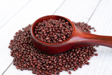 Azuki beans in wooden scoop on white table background