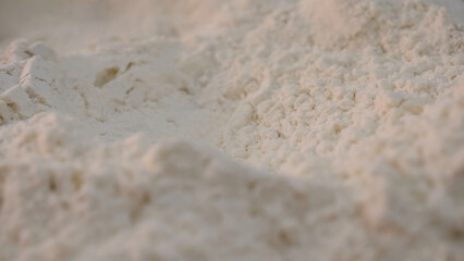 Fototapeta na wymiar Close-up of crumbly white flour. Stock footage. White pure flour is filtered before use in baking preparation. White dense but crumbly powder or flour