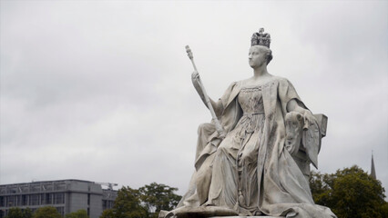 Queen monument on cloudy sky background. Action. Old beautiful sculpture of Queen of white stone in cloudy weather. Monument to great Queen