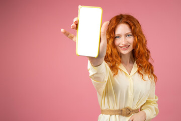 Picture of a happy redhead curly girl in yellow dress with a belt showing on camera phone with...