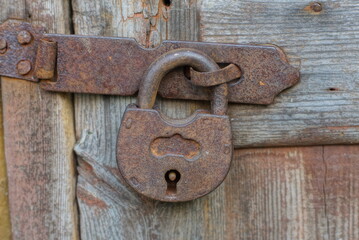 a rusty old lock hangs on a rusty old lock on an old unpainted door