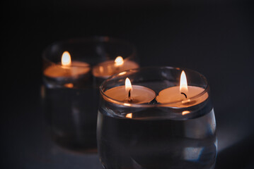 Fototapeta na wymiar lit candles on water in candlesticks