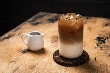 Cold iced latte coffee in the making. A tall highball glass filled with ice cubes and refreshing...