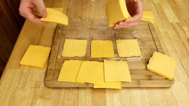 Splitting chunks of cheese singles into individual slices for repacking into smaller packages.