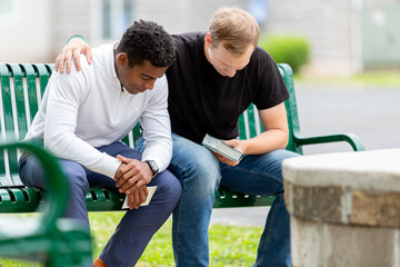 Two men praying on a bench - obrazy, fototapety, plakaty