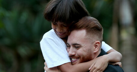 Beautiful child and father embrace, mixed race son hugging dad, authentic love and care relationship