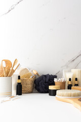 Fototapeta na wymiar Wooden toothbrushes with natural bristles in a ceramic glass, face and skin care products, black bottles with a pipette and a jar of cream, bath accessories, spa and beauty concept