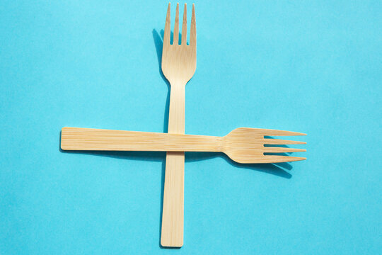 Wooden eco bamboo cutlery spoon and fork on bright blue background. Meal time concept