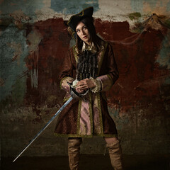 retro portrait of a musketeer girl in a hat with a sword.