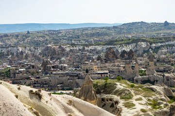 Fototapeta na wymiar Goreme town with fairy chimneys and mountains on the background in Cappadocia, Central Anatolia, Turkey. 