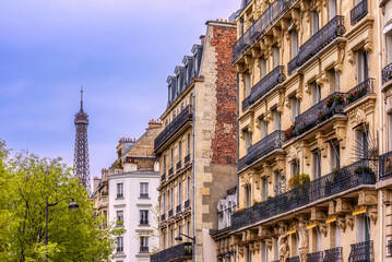 Traditional Parisian residential facades with the top of the Eiffel tower in the background 