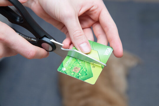 Syktyvkar, Komi, Russia,June 22, 2022,A man destroys an old credit card.The credit card is cut with scissors.