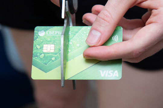 Syktyvkar, Komi, Russia,June 22, 2022,A man destroys an old credit card.The credit card is cut with scissors.