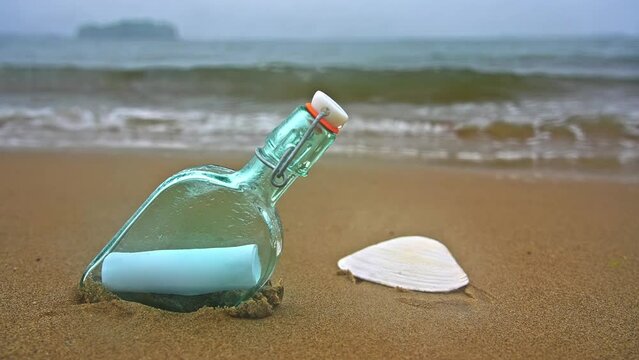 Bottle on beach with message on paper inside in rainy day