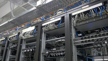 Fototapeta premium Device for mining crypto currency. Row of bitcoin miners set up on the wired shelfs. Mining cryptocurrency. Bitcoin farm. Machines for mining cryptocurrency, bitcoin. Electronic device at day