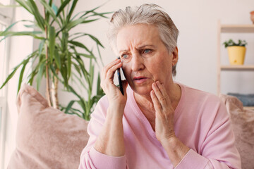 Unhappy stressed mature middle aged woman looking at phone screen