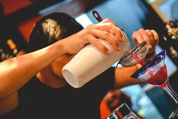 Closeup of young latin barman making a delicious cocktail in the bar from a pub in the night