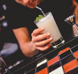 Closeup of young latin barman making a delicious cocktail in the bar from a pub in the night