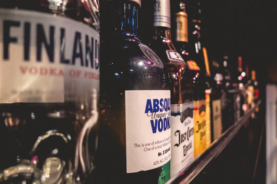 Closeup of bar shelf with bottles of Absolut Vodka, Finland Vodka and tequila Jose Cuervo